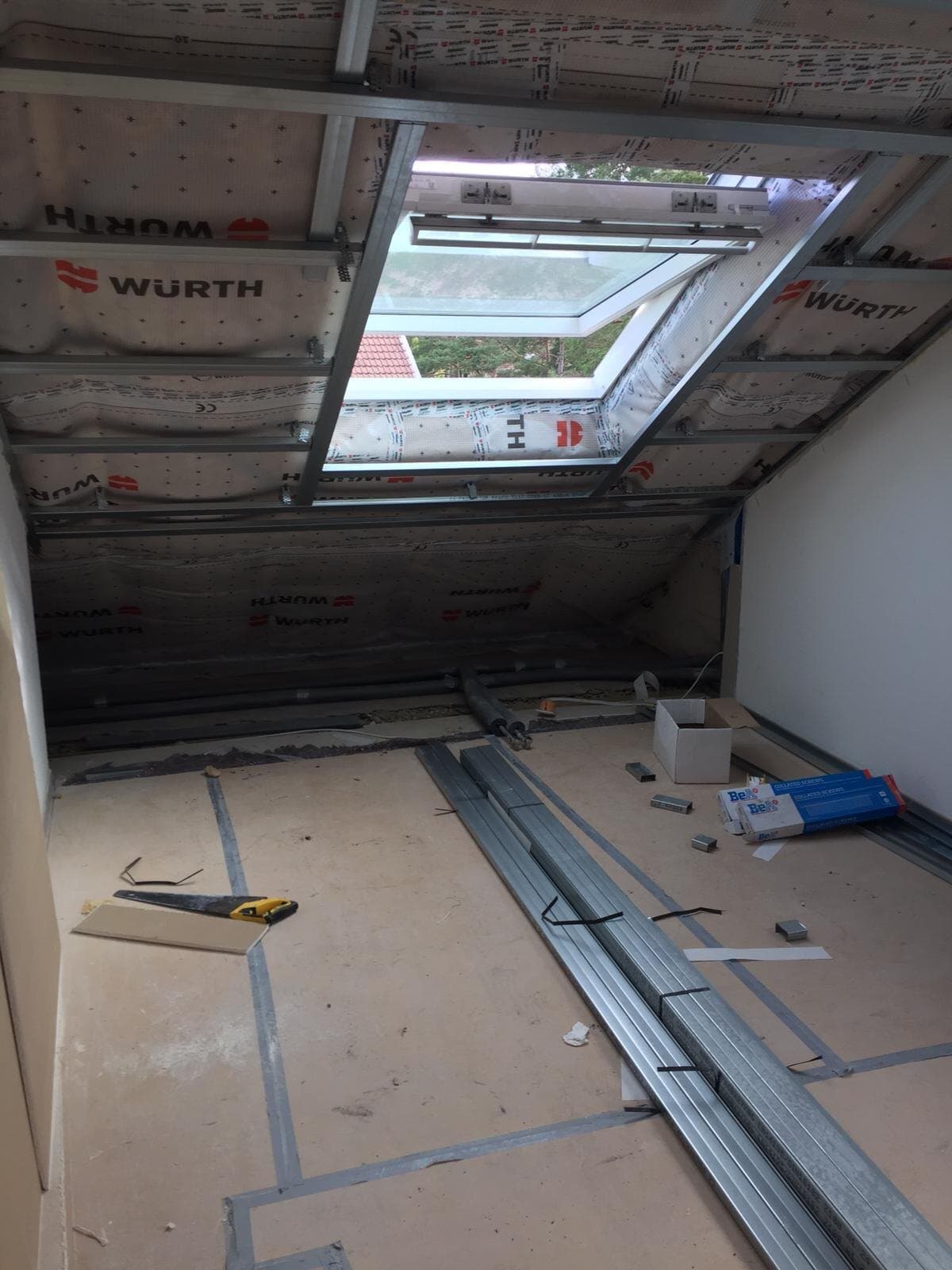 Dachgeschoss im Rohbau: Metallprofile, Dämmung und Folie an der Schräge, ein Dachfenster